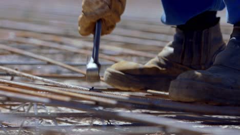 Construction-worker-ties-rebar-together-with-wire-to-create-a-reinforcing-grid-for-the-concrete-foundation