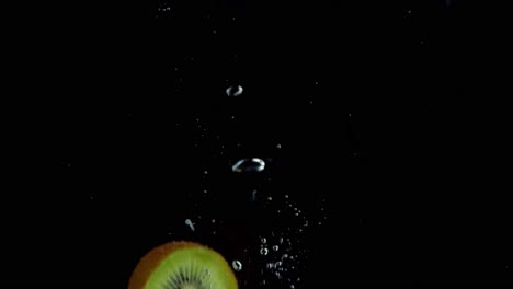 Kiwi-Fällt-Ins-Wasser-Super-Slowmotion,-Schwarzer-Hintergrund,-Viele-Luftblasen,-4k240fps