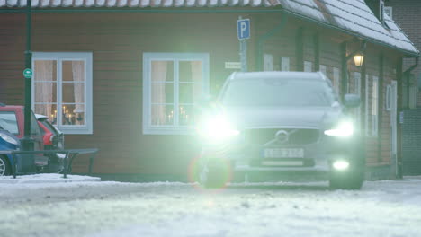 A-new-Volvo-pulls-up-in-front-of-an-old-traditional-Swedish-wooden-building-in-December,-during-the-covid-19-pandemic