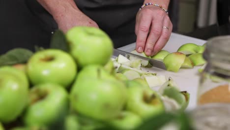 Hands-Cutting-Green-Apples-Into-Smaller-Portion-With-A-Sharp-Knife---close-up,-slow-motion