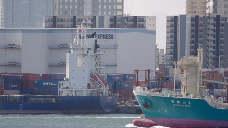 Eine-Feste-Einstellung-Eines-Tankschiffs,-Das-Von-Rechts-Nach-Links-Einen-Hafen-Passiert,-Mit-Einem-Containerhafen-Im-Hintergrund-In-Japan
