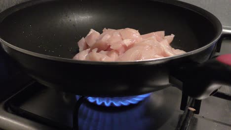 Gas-fire-burning-under-pan-filled-with-healthy-chicken-meat
