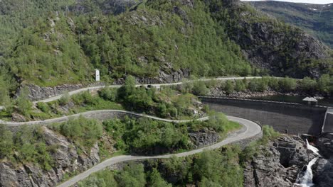 Aerial-Flying-backwards-Reveal-Small-dam-and-winding-Roads-on-the-hill---Bergsdalen