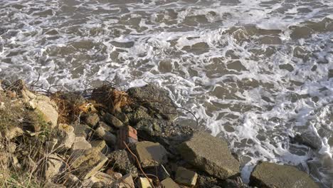 Ocean-Waves-Splashing-On-Pile-Of-Old-Damaged-Concrete-Blocks-And-Debris-On-Seashore