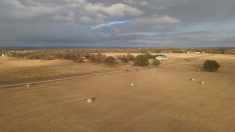 Drone-over-cloudy-Central-Texas-skies-with-open-fields-and-Bails-of-Hay
