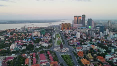 Aerial-flyover-Phnom-Penh-with-Independence-Monument-and-Mekong-River-during-dusk