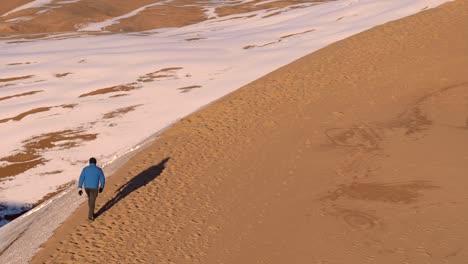 Man-walking-on-sand-dunes-in-slow-motion