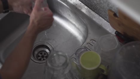 Washing-Tall-Transparent-Glass-And-Mug-On-A-Kitchen-Sink