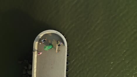 People-on-pier-with-small-green-lighthouse-and-breakwater