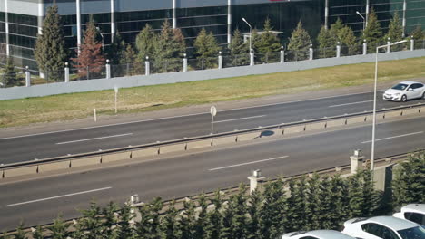 Top-view-of-Divided-Highway-with-Cars-passing-on-Double-Carriageways-near-Buildings-at-Daytime-in-slowmo