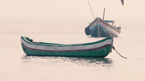 Small-wooden-boat-bobs-and-swings-on-calm-waves-in-sea-without-people-or-sailor,-a-small-boat-near-a-beach-shore-without-a-people-in-calm-waves-background-video-mov-in-full-HD