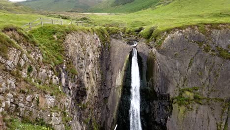 Time-lapse-shot-Of-Speke's-Mill-Mouth-Waterfall-with-rural-landscape-in-background