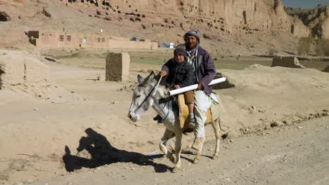 Local-Afgano-Montando-Un-Burro-Con-Su-Hijo-En-Bamyan,-Afganistán---Mano,-Plano-Medio