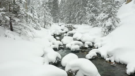 jib-up-of-calm-creek,-revealing-snow-covered-landscape
