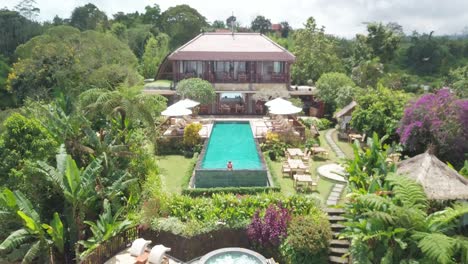 Luftaufnahme,-Junge-Frau-Im-Schwimmbad-Einer-Luxusvilla-Auf-Der-Insel-Bali,-Exotisches-Tropisches-Urlaubskonzept,-Aufschlussreiche-Drohnenaufnahme
