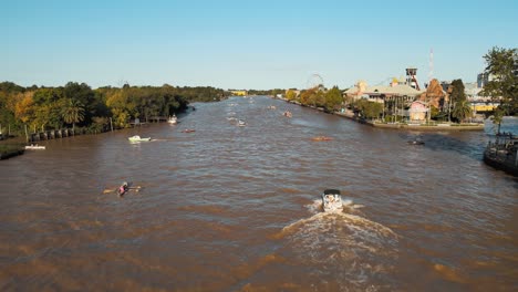 Traditional-Boat-Cruising-At-Lujan-River-Passing-By-People-Rowing-Boat-In-Tigre,-Buenos-Aires,-Argentina