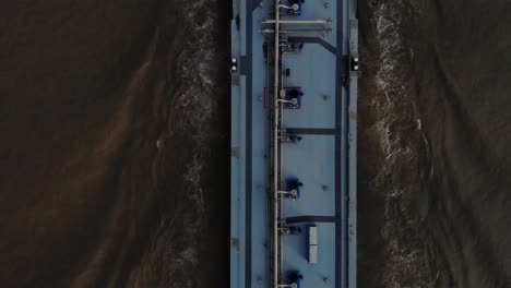 Heavy-loaded-blue-tanker-sailing-foreward-on-a-dark-colored-river-using-it-navigating-radar