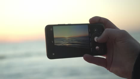 Eine-Person-Fängt-Mit-Ihrem-Mobiltelefon-Den-Sonnenuntergang-über-Sylt-Ein