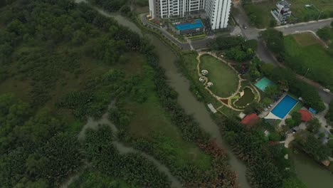 drone-shot-flying-over-wetlands-to-a-modern-high-rise-development-on-the-outskirts-of-Ho-Chi-Minh-City,-Vietnam-with-rice-fields-in-the-background
