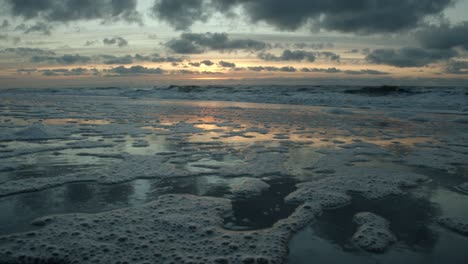 Sonnenuntergang-über-Der-Nordsee-Auf-Sylt-Mit-Nassem-Sand-Im-Vordergrund,-In-Dem-Sich-Die-Sonne-Und-Die-Wolken-Spiegeln
