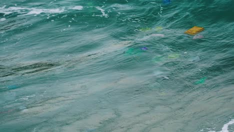 Close-up-on-sea-wave-carry-plastic-rubbish-polluting-environment