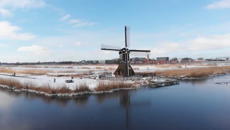Iconic-Dutch-windmill-in-winter-snow-scene-landscape,-aerial-view