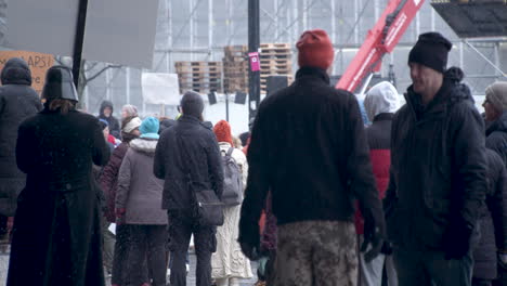 Medium-wide-shot-of-people-gathering-to-protest-in-Helsinki,-some-carrying-large-placards