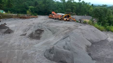 Dump-trucks-and-excavators-parked-in-open-pit-sand-mine-in-Magelang,-Indonesia