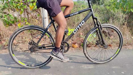 An-Indian-Young-cyclist-moving-fast-in-bicycle-in-middle-of-the-countryside-road-with-plants-and-mangroves-in-background,-sports-and-fitness,-workout,-exercise,-training-concept-youth