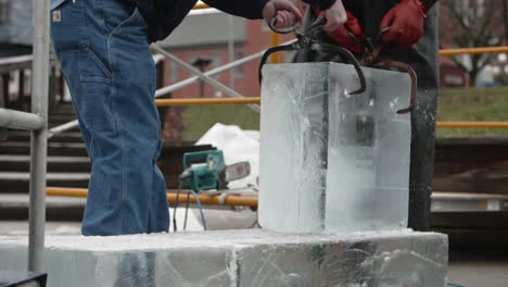 Ice-sculptor-and-assistant-moving-large-block-of-ice,-Slow-Motion