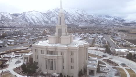 Aerial-view-of-Payson-Utah-Temple-with-snowy-mountains,-wide-circle-shot