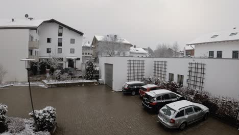 Verschneiter-Winter-Zeitraffer-Einer-Städtischen-Szene-Mit-Schnee-Auf-Den-Dächern-Von-Häusern-Und-Schneebedeckten-Autos-Auf-Einem-Zentralen-Parkplatz