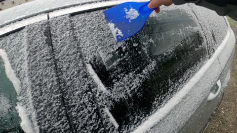 Cleaning-the-side-car-windows-of-snow-with-ice-scraper-before-the-trip