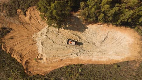 4K-aerial-view-of-a-bulldozer-moving-some-earth-in-the-middle-of-the-forest,-heavy-duty-machinery