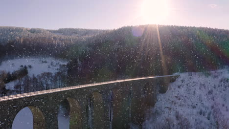 Arches-of-a-stone-railway-viaduct-in-winter-mountains-in-falling-snow