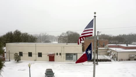 Rotierende-Aufnahme-Der-US-Flagge-Und-Der-Texas-Flagge,-Die-Zusammen-Mit-Dem-Schneegestöber-Im-Wind-Wehen