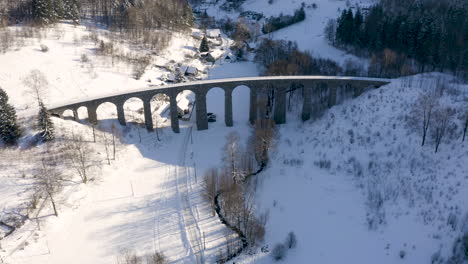 Steinbahnviadukt-über-Einem-Flusstal-Im-Winter,-Verschneite-Landschaft