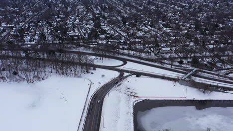 An-aerial-view-from-a-drone,-over-a-cleared-road-with-a-frozen-lake-on-either-side
