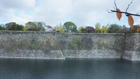 Osaka-Castle-Moat-Walls,-Pan-Across-Ancient-Tall-Defense-Structure,-Japan
