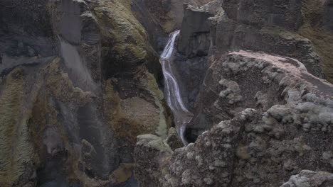 High-angle-of-waters-flowing-between-rock-walls-of-Fjadrargljufur-Canyon,-Iceland