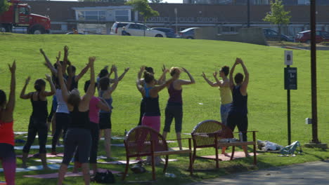Yoga-Class---Yogi-Instructor-With-Group-Of-People-Stretching-Before-Practicing-Yoga-At-Durham-City-Park-In-USA