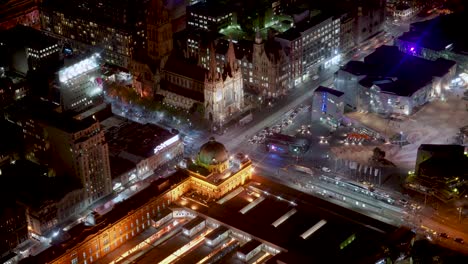 Night-timelapse-with-of-Flinders-Station,-Paul-Cathedral-and-Federation-Square-of-Melbourne-City-filled-with-movements-from-pedestrians,-traffics,-and-trams-from-Eureka-Tower-on-loop