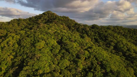 4k-drone-flying-backwards-while-panning-sideways-revealing-stunning-sunset-over-remote-landscape-covered-by-lush-rainforest