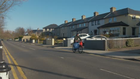 Hombre-En-Bicicleta-Por-Una-Calle-Tranquila-En-Irlanda-Con-Bolsas-De-Supermercado