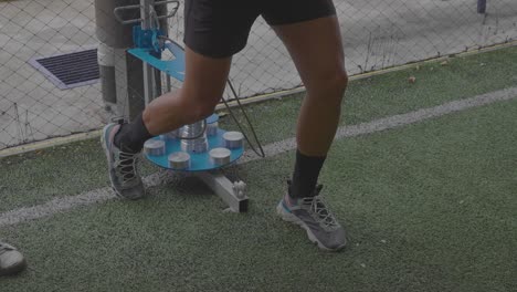 Man-training-his-arms-and-legs-with-conical-pulley-on-synthetic-turf