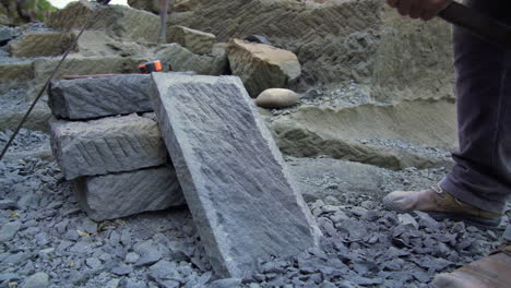 Freihandaufnahme-Eines-Handwerkers,-Der-Mit-Einer-Handhacke-Eine-Steinplatte-Zerhackt,-Aufgenommen-Draußen-In-Der-Stadt-Ancud-Auf-Der-Insel-Chiloé