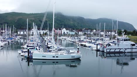 Luxury-yachts-and-sailboats-parked-on-misty-mountain-range-retirement-village-marina-descending-shot