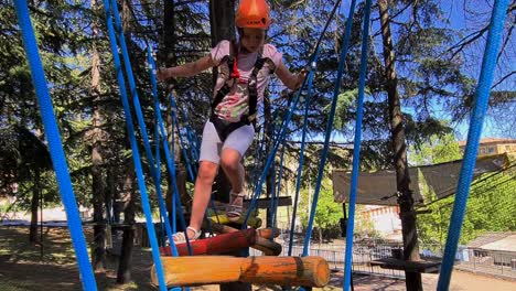 Niña-Valiente-Experimentando-Obstáculos-En-Movimiento-En-El-Parque-De-Aventuras-De-Cuerdas-Para-Niños