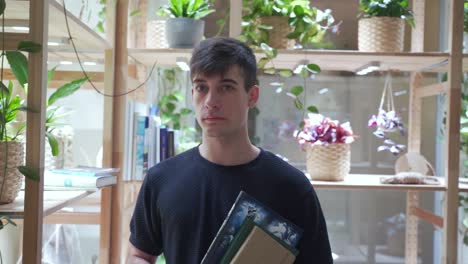 Portrait-of-blach-hair-male-student-stands-holding-books-in-the-library