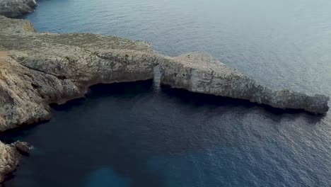 Beautiful-Arch-Of-Natural-Rock,-Pont-d'en-Gil-In-Menorca,-Spain---aerial-sideways